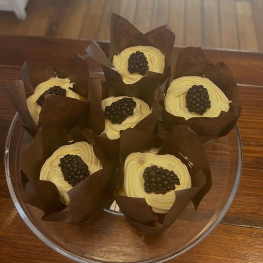 Cupcakes piped with cream and topped with a blackberry
