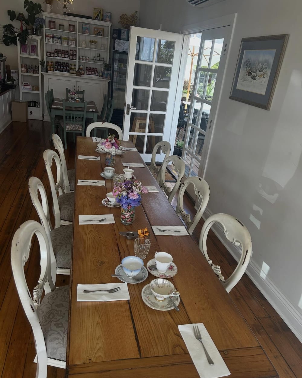 The long communal timber table inside The Epicurean Cafe, set with teacups