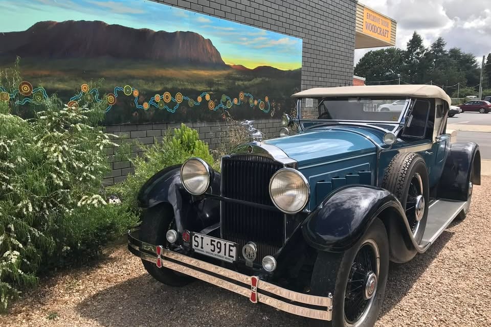 The Echo of the Mountains mural in Sheffield, with a vintage car parked in front